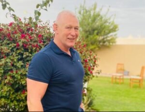 Mark Jones smiling in his later years, standing in a garden